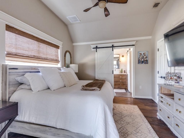 bedroom featuring lofted ceiling, a barn door, and visible vents