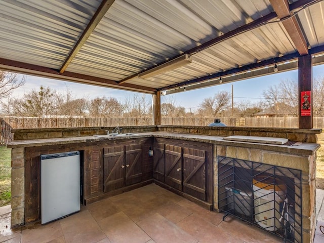 view of patio featuring fence, an outdoor kitchen, and a sink