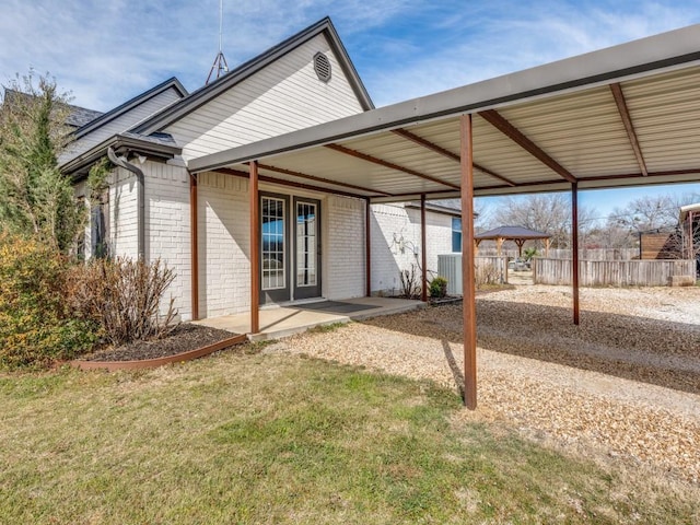 back of property with a carport, brick siding, and fence