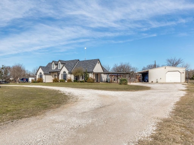 view of front facade featuring a garage, an outbuilding, dirt driveway, and a front lawn