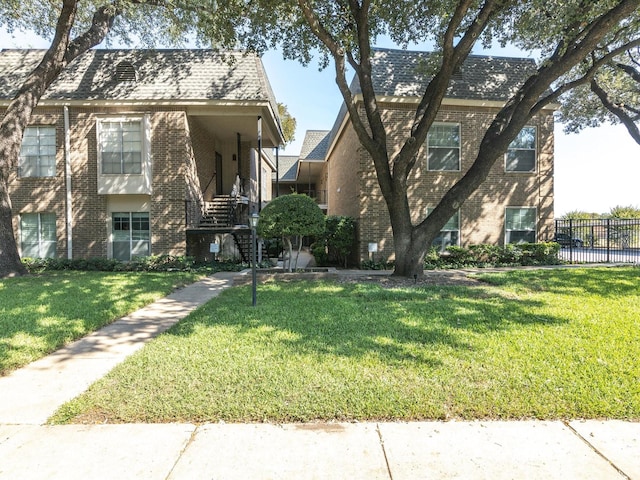 view of front of home with brick siding, a front lawn, and fence