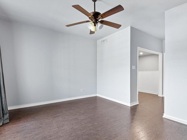 spare room featuring a ceiling fan, visible vents, dark wood finished floors, and baseboards