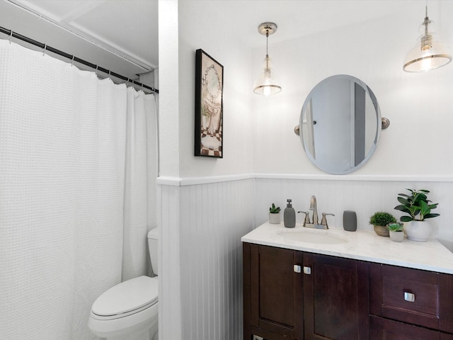 full bathroom featuring wainscoting, vanity, and toilet