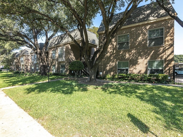 view of side of home with brick siding and a yard