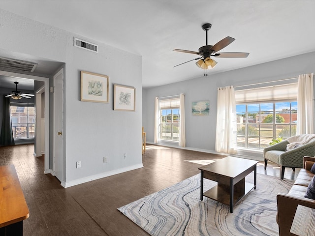 living room featuring baseboards, ceiling fan, visible vents, and wood finished floors