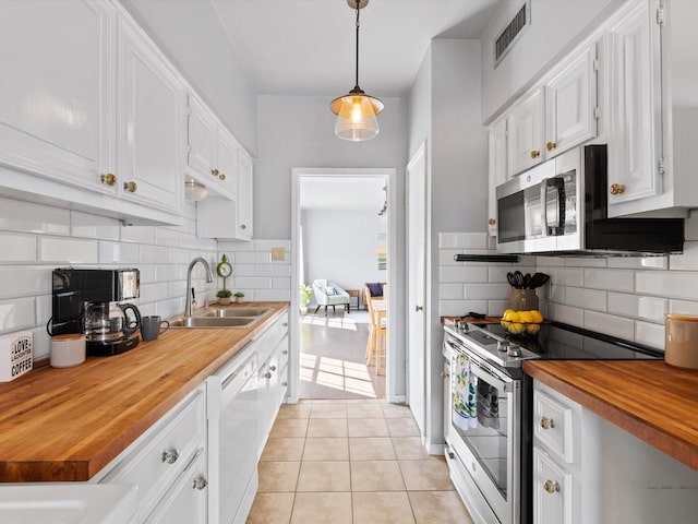 kitchen with light tile patterned floors, stainless steel appliances, visible vents, a sink, and butcher block countertops