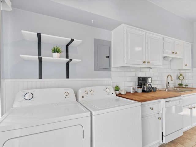 laundry room with laundry area, electric panel, wainscoting, washing machine and dryer, and a sink