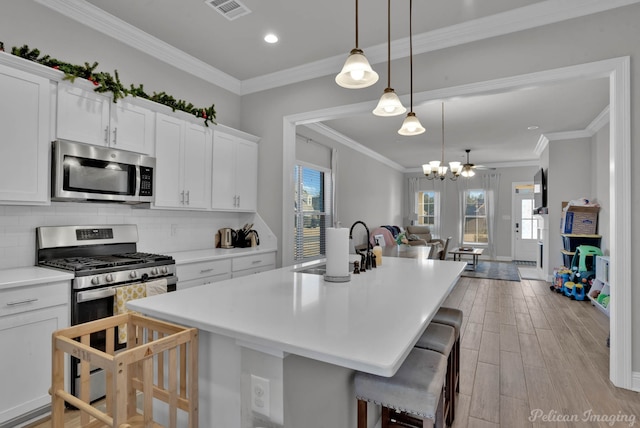 kitchen featuring stainless steel appliances, visible vents, backsplash, light wood-style flooring, and a kitchen island with sink