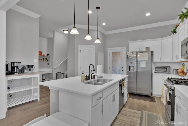 kitchen featuring light wood finished floors, light countertops, appliances with stainless steel finishes, white cabinetry, and a sink