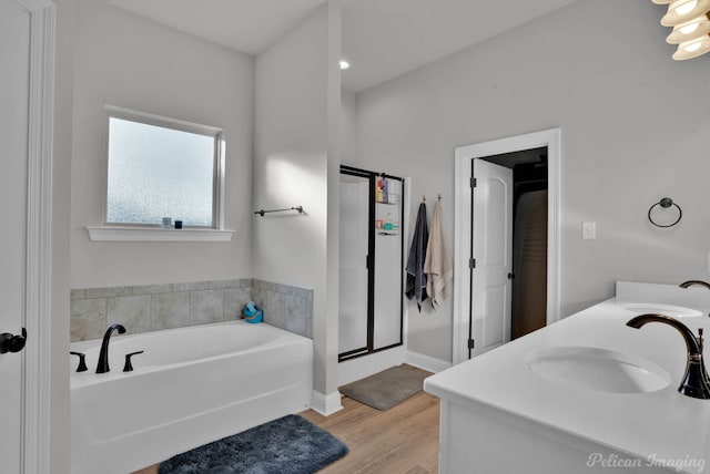 bathroom with a garden tub, a shower stall, a sink, and wood finished floors