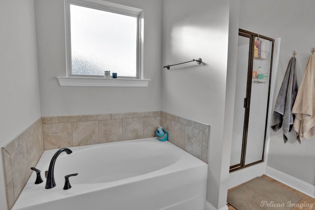 full bathroom featuring a stall shower, a garden tub, and baseboards