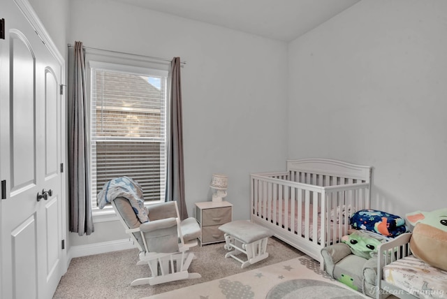 carpeted bedroom featuring a nursery area and baseboards