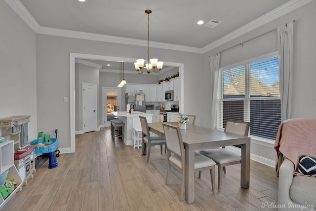 dining area featuring visible vents, crown molding, and light wood-style flooring