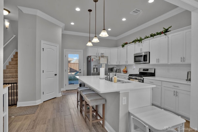 kitchen featuring light wood finished floors, decorative backsplash, stainless steel appliances, and a sink