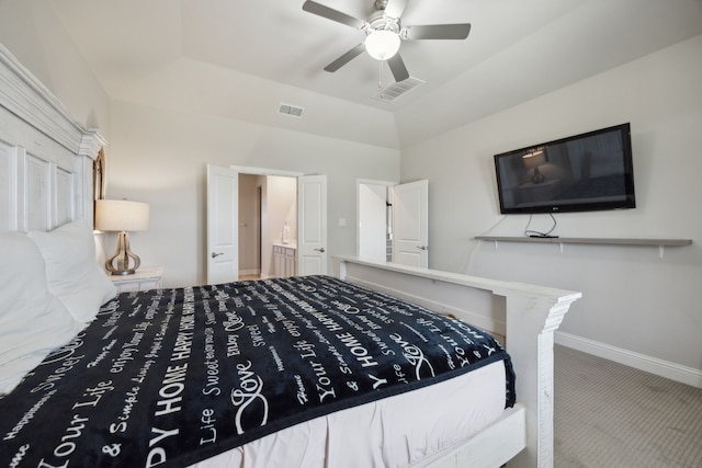 carpeted bedroom featuring a ceiling fan, ensuite bath, visible vents, and baseboards