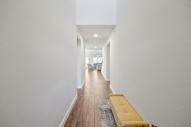 corridor with baseboards and wood finished floors