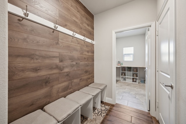 mudroom with wood walls and wood finished floors