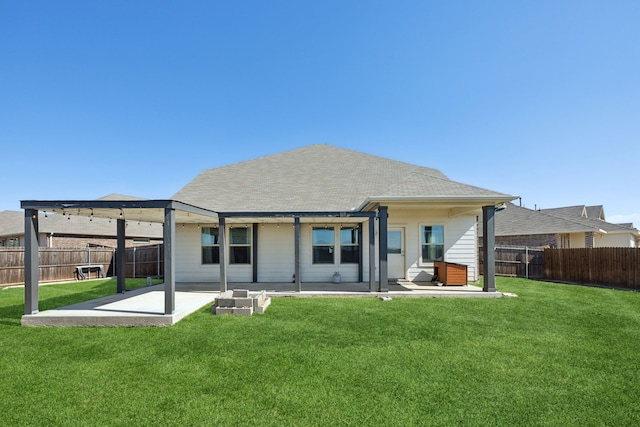 rear view of house with a yard, a fenced backyard, roof with shingles, and a patio