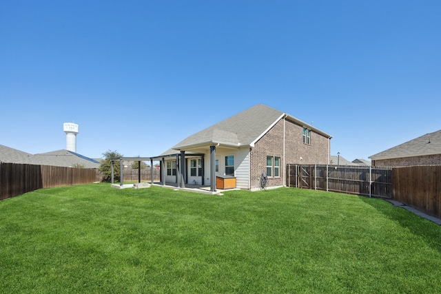 rear view of house with a yard, brick siding, and a fenced backyard