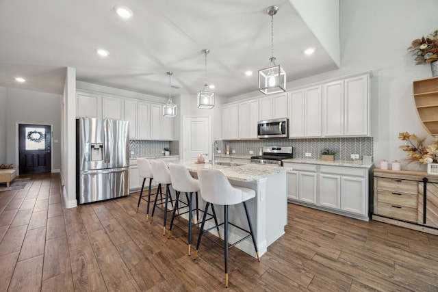 kitchen featuring white cabinetry, appliances with stainless steel finishes, a breakfast bar, and dark wood-style flooring