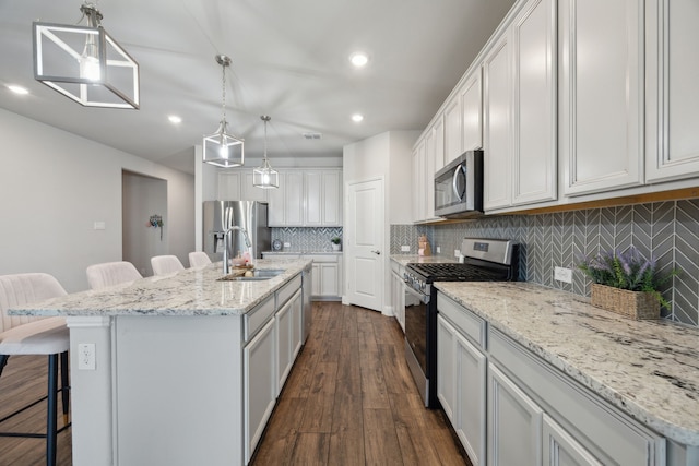 kitchen with dark wood-style flooring, a breakfast bar area, tasteful backsplash, appliances with stainless steel finishes, and a sink