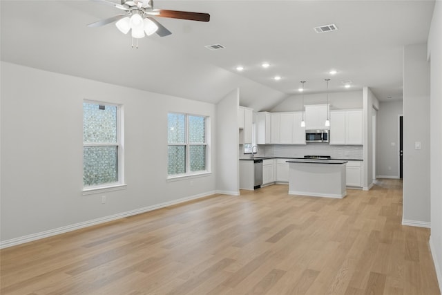 kitchen with lofted ceiling, open floor plan, backsplash, dark countertops, and appliances with stainless steel finishes