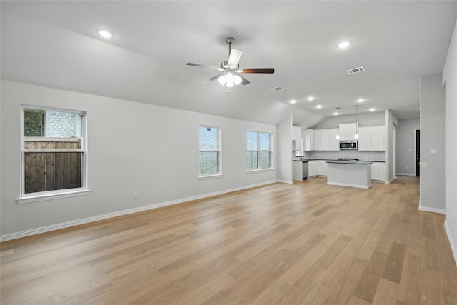 unfurnished living room with a ceiling fan, baseboards, visible vents, vaulted ceiling, and light wood-type flooring