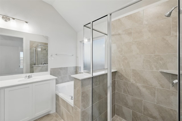 bathroom featuring vaulted ceiling, vanity, a garden tub, and a shower stall