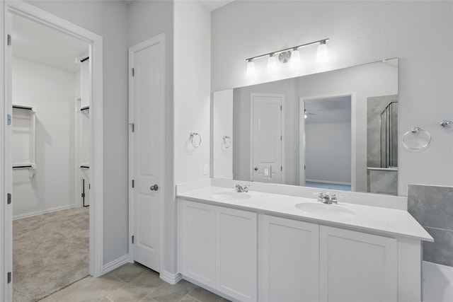 bathroom featuring a sink, double vanity, a shower with shower door, and ceiling fan