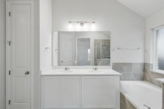 full bath with a garden tub, lofted ceiling, a shower stall, and a sink