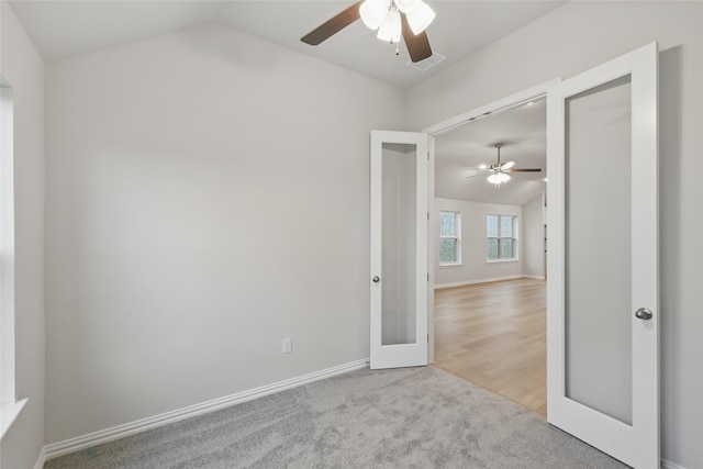 carpeted spare room featuring a ceiling fan, baseboards, french doors, and vaulted ceiling