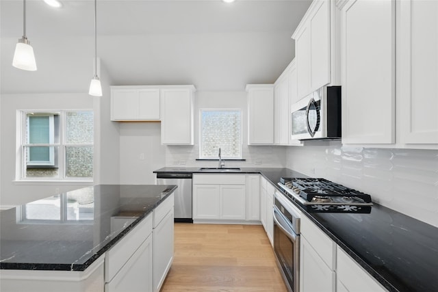 kitchen with white cabinetry, stainless steel appliances, decorative backsplash, and a sink