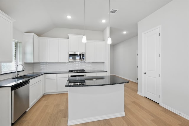 kitchen featuring a sink, white cabinetry, decorative backsplash, a kitchen island, and appliances with stainless steel finishes