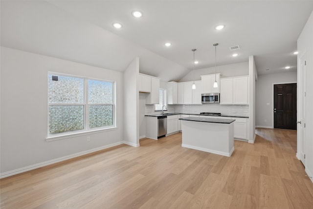 kitchen featuring light wood-type flooring, visible vents, white cabinetry, appliances with stainless steel finishes, and lofted ceiling