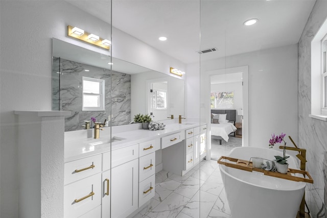 full bath featuring double vanity, a freestanding bath, and a sink