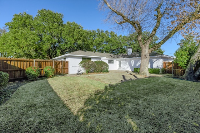 back of property with a fenced backyard, a yard, and a chimney