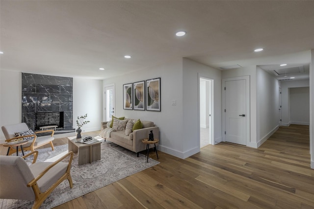 living room featuring baseboards, a fireplace, wood finished floors, and recessed lighting