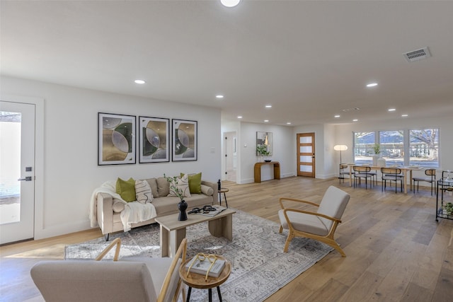 living area with recessed lighting, baseboards, visible vents, and light wood finished floors