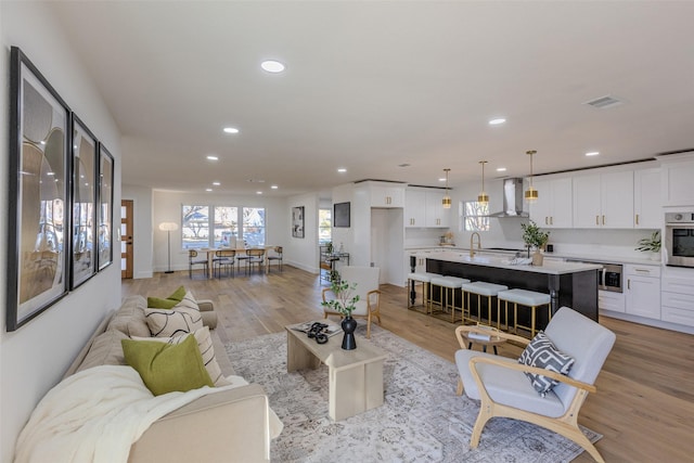 living room featuring recessed lighting, visible vents, light wood-style flooring, and baseboards