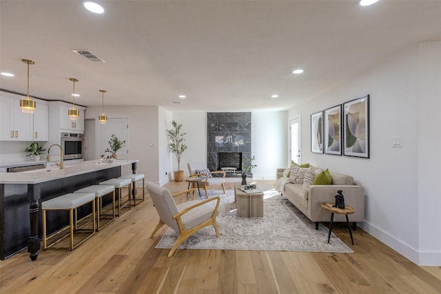 living room with light wood-type flooring, visible vents, a fireplace, and recessed lighting