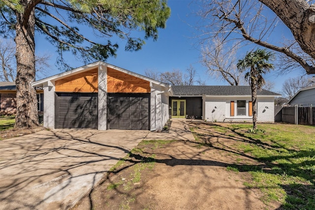 view of front of house featuring driveway, an attached garage, fence, french doors, and brick siding