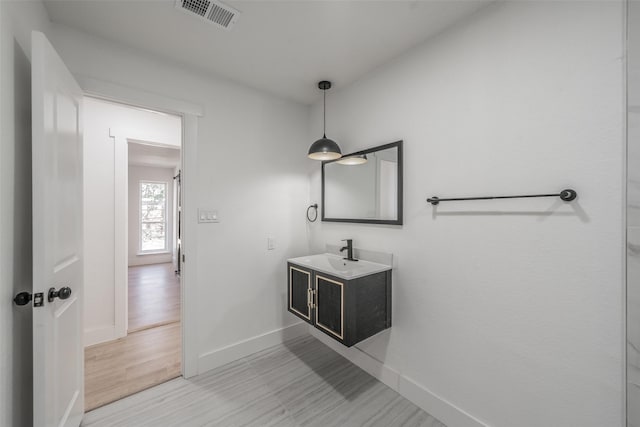 bathroom featuring baseboards, visible vents, wood finished floors, and vanity