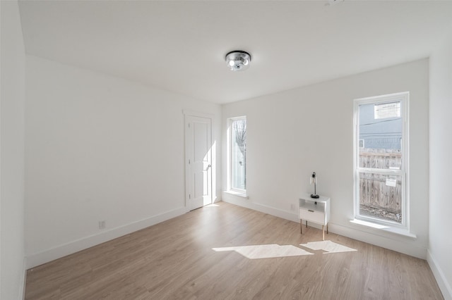 spare room featuring a wealth of natural light, baseboards, and wood finished floors