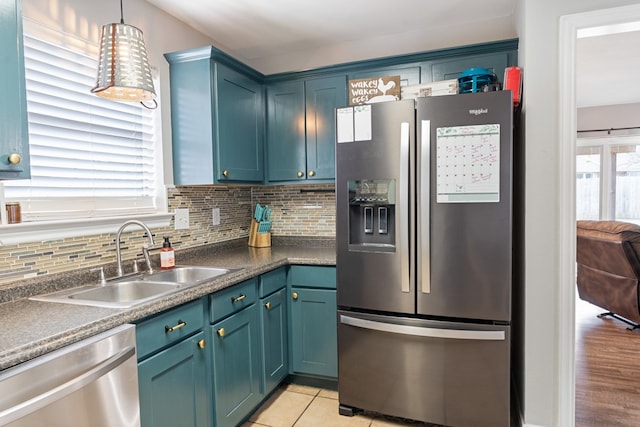 kitchen featuring a sink, hanging light fixtures, appliances with stainless steel finishes, backsplash, and dark countertops