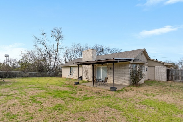 back of house featuring a fenced backyard, brick siding, a lawn, a chimney, and a patio area