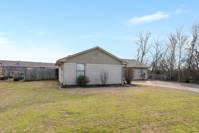 view of home's exterior featuring brick siding, fence, driveway, and a lawn