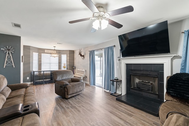 living area with baseboards, a fireplace, visible vents, and wood finished floors