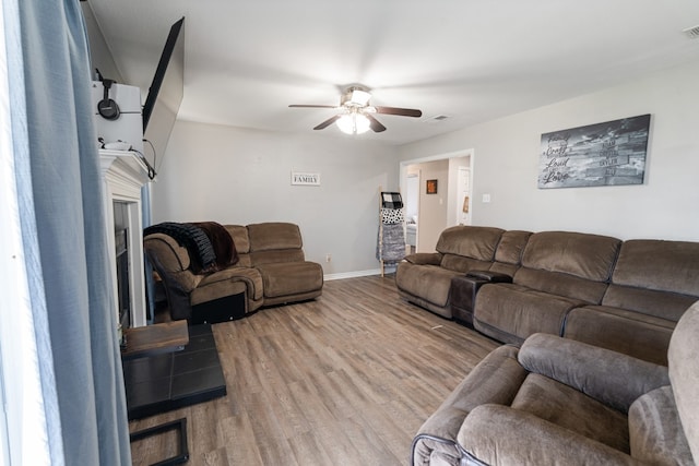 living room with ceiling fan, a fireplace, wood finished floors, and visible vents