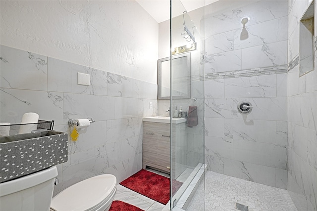 full bathroom with tile walls, tiled shower, vanity, and toilet