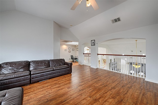 living room featuring ceiling fan, visible vents, vaulted ceiling, and wood finished floors